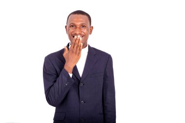 Ceketli yakışıklı iş adamı beyaz arka planda, elleri ağızda kameraya bakıp gülümsüyor..