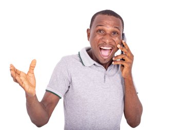 Yakışıklı, mutlu, genç bir adam. Kapalı bir yerde duruyor ve cep telefonunda gülümsüyor..