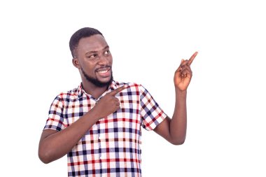 Beyaz arka planda duran bez gömlekli yakışıklı genç bir adam gülümserken parmak hareketleriyle bir şey gösteriyor..