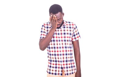 handsome serious adult man standing in sad shirt with head fucked closing one eye with his hand.