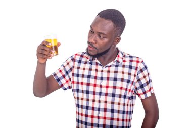 Yakışıklı yetişkin bir adam elinde buzlu bira bardağıyla tişörtle dikiliyor..