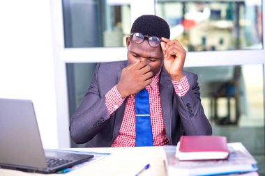 Ceketli yakışıklı iş adamı masasında oturmuş burnunu ovalıyor..