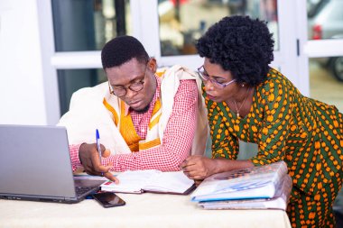 İş adamı ve iş kadını bilgisayar karşısında oturup ofisteki bir belgenin raporlarını kontrol ediyorlar..