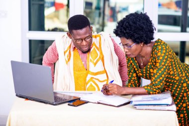 İşadamı ve iş kadını laptopta çalışıyor ve ofiste raporları birlikte kontrol ediyorlar..