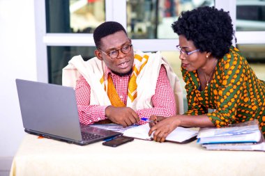 İşadamı ve iş kadını laptopta çalışıyor ve ofiste raporları birlikte kontrol ediyorlar..