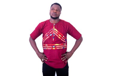 Yakışıklı dalgın genç adam kırmızı gömlekli ve ellerini kalçasında tutuyor..