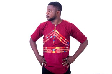 Yakışıklı düşünceli genç adam kırmızı gömlekli ve ellerini kalçasında tutuyor..