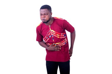 Peştamal gömlek giyen yakışıklı bir adam beyaz arka planda duruyor karın ağrısı içinde kıvranıyor..