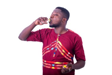 Beyaz arka planda duran peştemalli yakışıklı bir adam alkol içiyor..