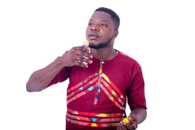 Beyaz arka planda duran peştemalli yakışıklı bir adam alkol içiyor..