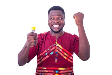 Beyaz arka planda duran peştemalli yakışıklı bir adam elinde bir şişe likör tutarak gülüyor..