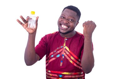 Geleneksel tişörtlü yakışıklı genç adam elinde küçük bir şişe tutuyor ve güzel bir jest yapıyor..