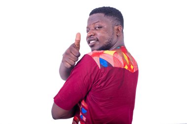 Arkasından genç ve yakışıklı bir adam kameraya gülümserken başparmağını omzunun üzerinden gösteriyor..