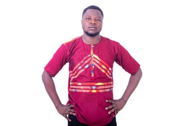 Geleneksel tişörtlü yakışıklı genç adam ellerini kalçasında tutuyor ve kameraya bakıyor..