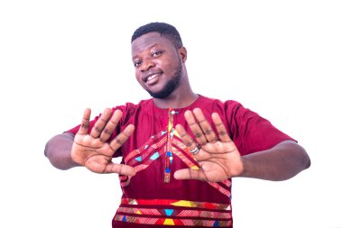 Geleneksel gömlekli yakışıklı genç adam, ellerini kameraya gösteriyor, gülümsüyor..