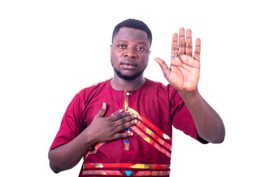 Geleneksel samimi gömlekli yakışıklı genç adam avuç içini kaldırıyor ve elini göğsüne koyuyor..