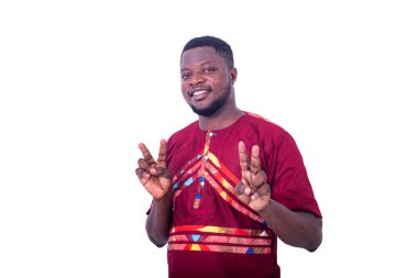 Beyaz arka planda duran peştemalli yakışıklı genç adam zafer işareti gösterirken gülümsüyor..