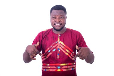 Peştamal gömlekli yakışıklı genç adam beyaz arka planda duruyor parmaklarıyla hareket ediyor ve kameraya bakıp gülümsüyor..