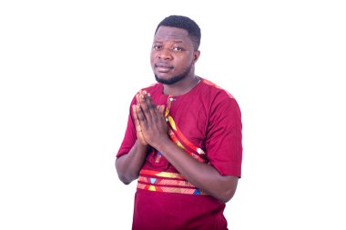 Beyaz arka planda duran peştemalli genç adam katlanmış elleriyle kameraya bakıyor..