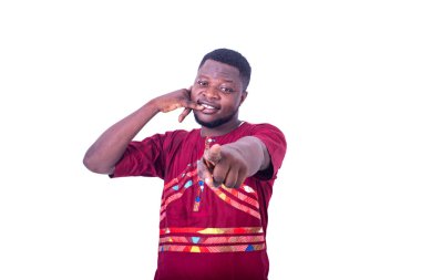 Beyaz arka planda duran peştemalli yakışıklı genç adam telefon hareketlerinde bulunuyor ve gülümseyen birini işaret ediyor..