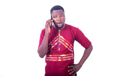 Şaşırmış genç bir adam cep telefonuyla konuşuyor..