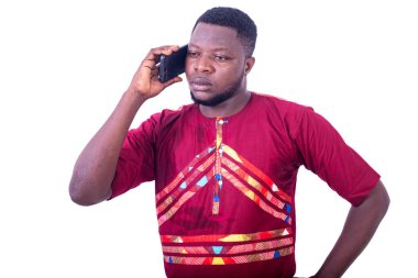 Geleneksel elbiseli ve cep telefonuyla konuşan yakışıklı, ciddi bir yetişkin adam.