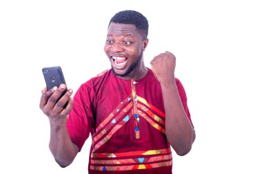 Yakışıklı, mutlu, yetişkin bir adam gülümserken cep telefonu tutarken zafer jesti yapıyor..