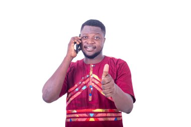 Kameraya gülümserken başparmağıyla cep telefonuyla konuşan yakışıklı, mutlu yetişkin bir adam.