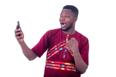 Cep telefonu kullanan yakışıklı genç adam zafer jesti yapıyor..