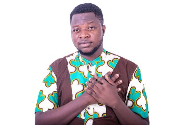 Yakışıklı, ciddi, genç bir adam ellerini göğsüne koyup kameraya bakıyor..