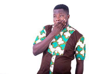 Peştamal gömlekli genç bir işadamı beyaz arka planda durup eli ağızda olan bir şeye bakıyor..