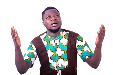 Peştamal gömlekli genç adam beyaz arka planda duruyor ve elleri havada dua ediyor..