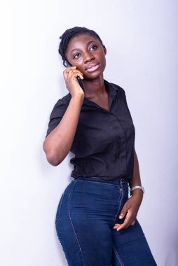 Beyaz arka planda duran genç bir öğrenci cep telefonuyla iletişim kuruyor.