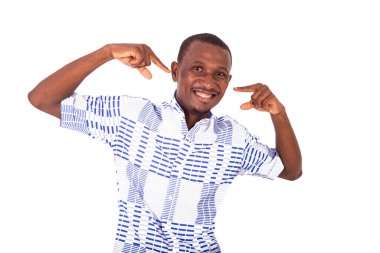 Mutlu genç adam kameraya gülümserken parmağıyla yüzünü gösteriyor..