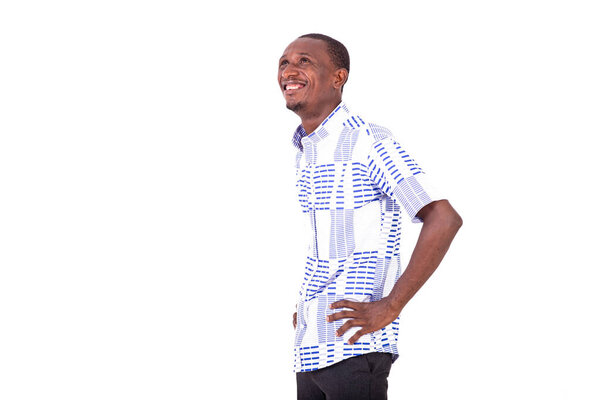Young happy man standing sideways keeping hands on his hips and looking upwards smiling.