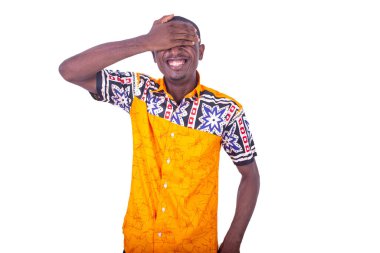 Kolsuz tişört giyen yakışıklı genç bir işadamı beyaz bir arka planda durup elini yüzüne sürerek gülüyor.