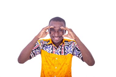 Beyaz arka planda duran yakışıklı, genç bir işadamı kameraya bakıp komik bir yüz ifadesi takınıyor.