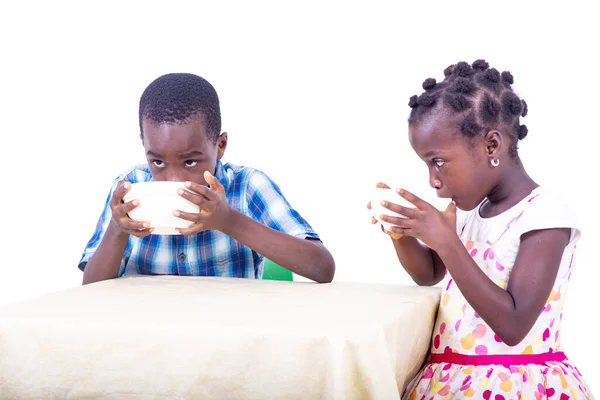 2人のかわいい子供が家でミルクを飲みながら朝食を食べながらテーブルに座って — ストック写真