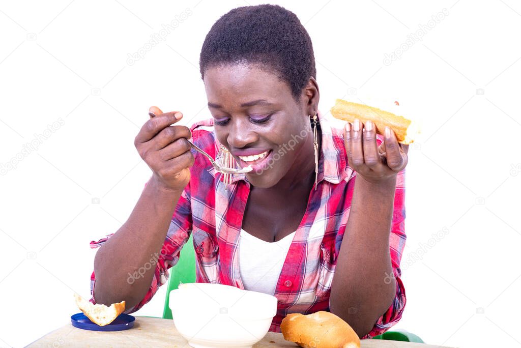 beautiful young woman sitting at the table having breakfast while eating a piece of bread and drinking coffee.