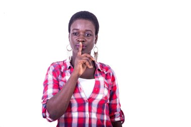 young beautiful woman in checkered shirt standing on white background showing sign of silence by putting finger on mouth