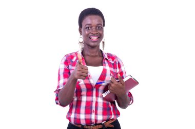 beautiful young woman holding a notebook and showing her thumb while smiling at the camera.