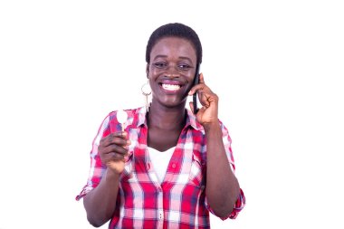 portrait of a beautiful young woman talking on mobile phone while holding yogurt on a small wooden board.