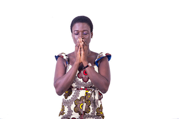 A beautiful young african woman in a loincloth dress standing on a white background praying