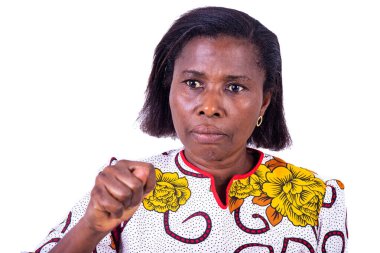 Beyaz bir arka planda duran ve mutsuz bakışlarla yumruğunu gösteren, çiçek takmış olgun bir kadın.