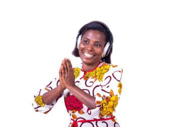 Beyaz arka planda duran bir kadın müzik ritmine göre dans ederken kulaklıkların yardımıyla gülüyor.