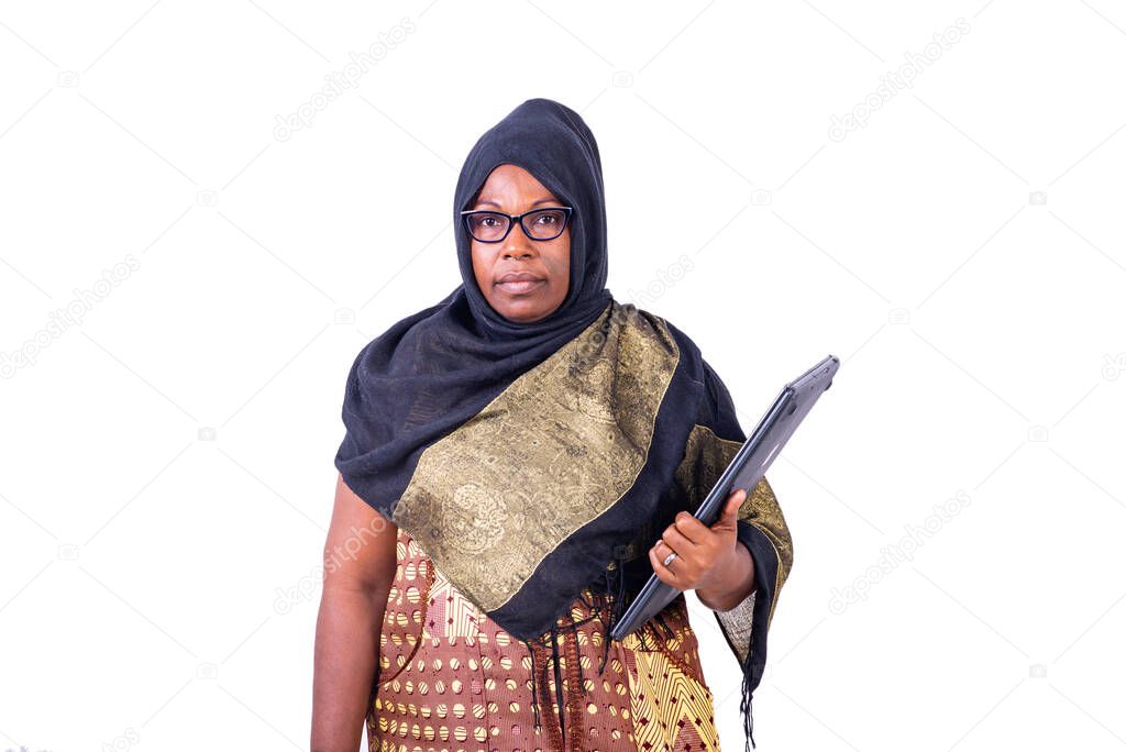 Muslim mature businesswoman, wearing glasses, holding laptop and looking at camera.