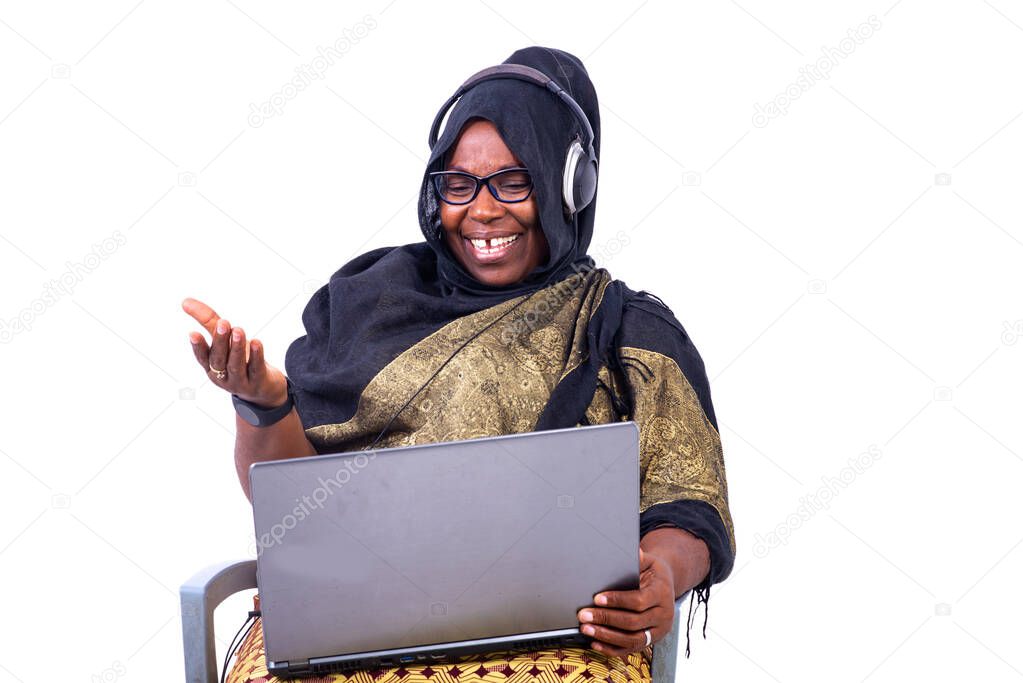 beautiful muslim businesswoman sitting on white background laughing using laptop and headphones.