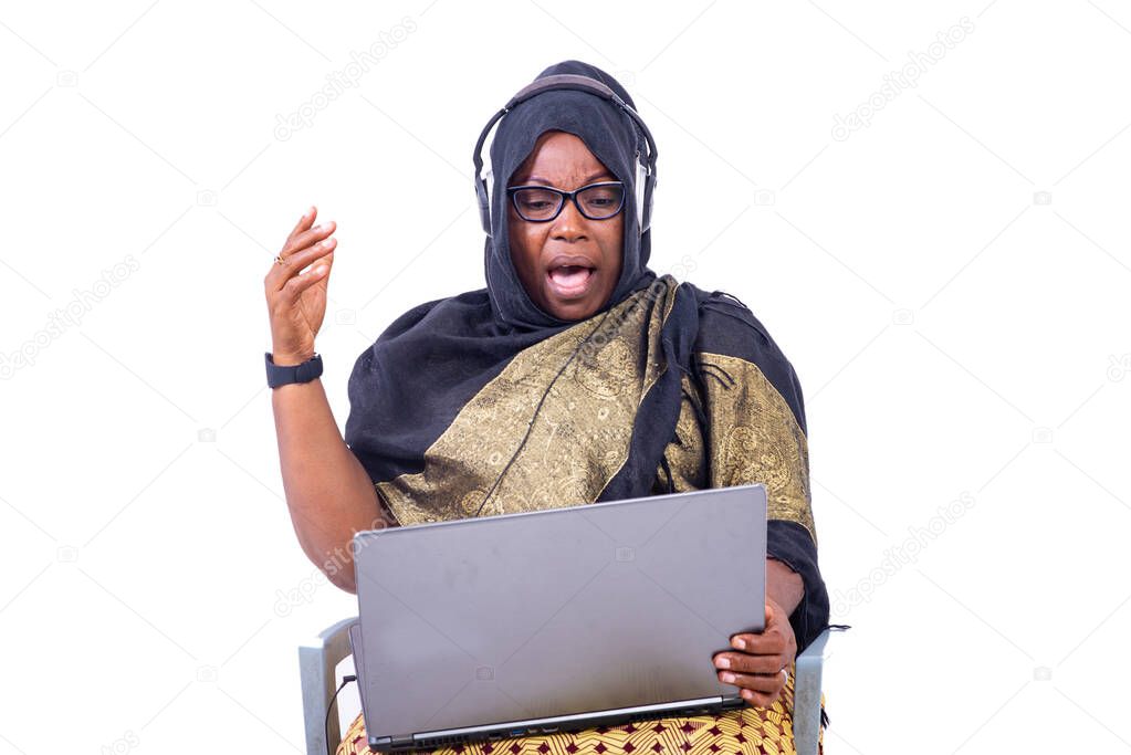 beautiful muslim businesswoman sitting on white background communicating using laptop and headphones looking surprised.