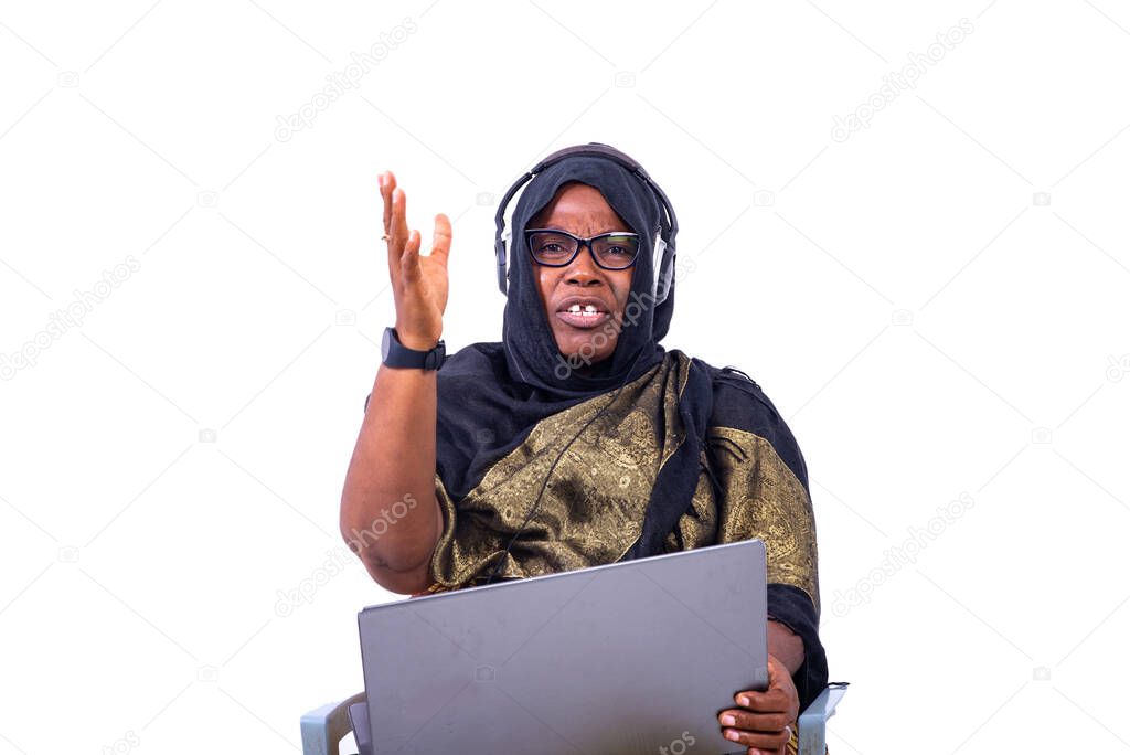 beautiful muslim businesswoman sitting on white background communicating using laptop and headphones with angry look.