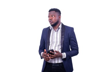 Genç, ciddi bir iş adamı takım elbise giyiyor ve elinde bir cep telefonuyla yan tarafa bakıyor..